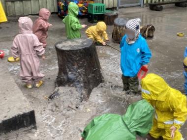 Børn der leger med mudder og vand i regntøj